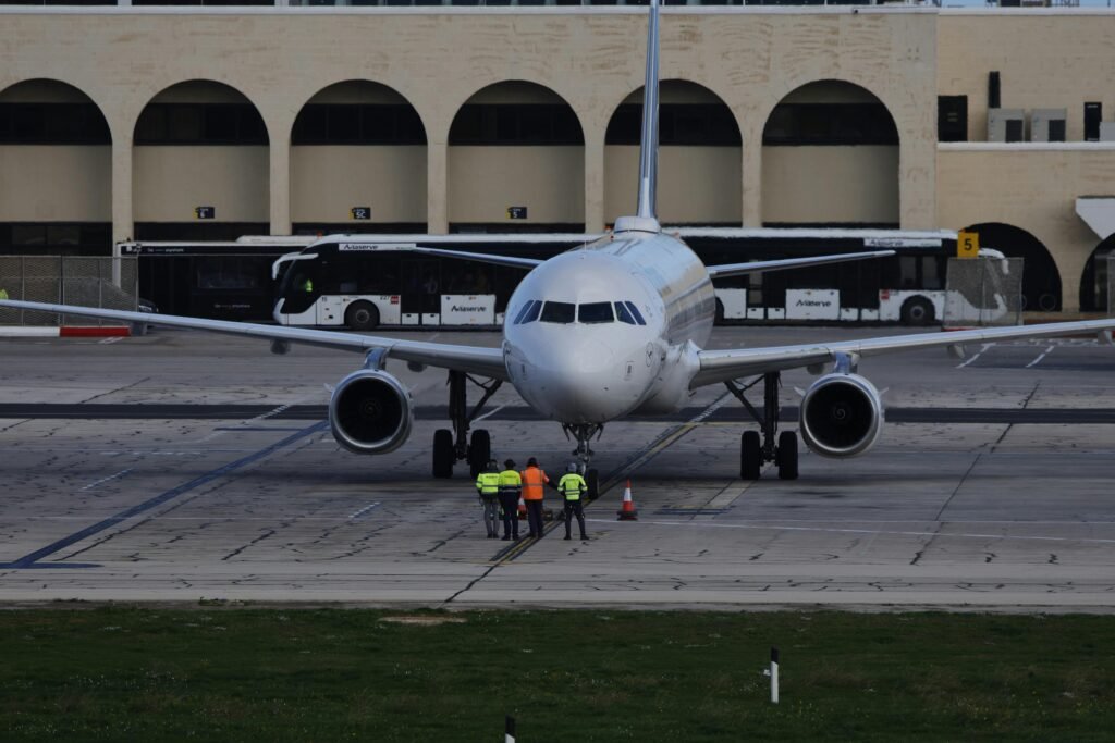 Front view of a commercial airplane on the taxiway with ground crew in reflective vests.